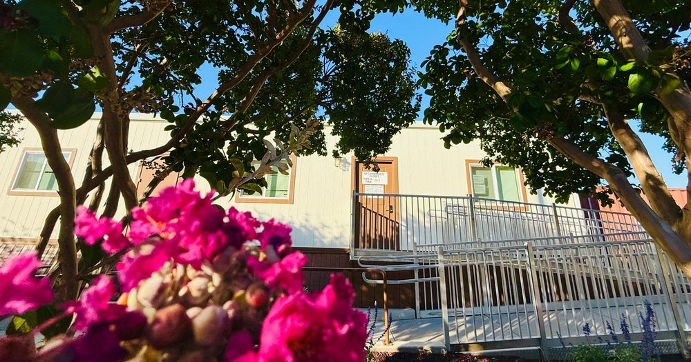 St. Catherine's Community Closet building, with its door sign and a flowering tree